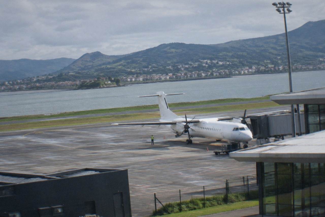 A small regional airport terminal at dusk with a turboprop aircraft parked at the gate