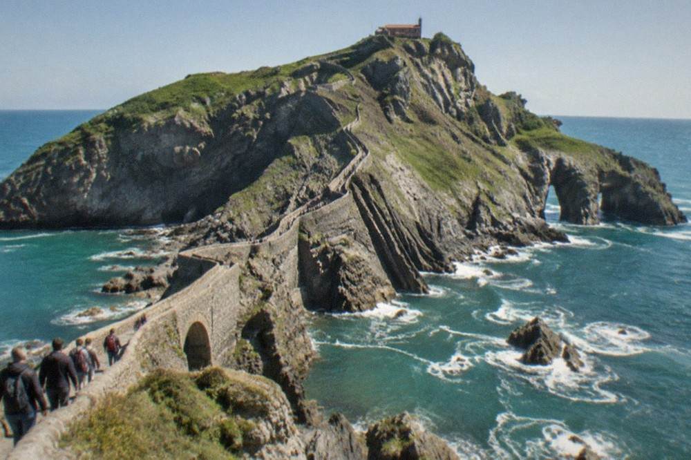 Visitors walking the long stone staircase toward the small hermitage at the top of the Gaztelugatxe islet