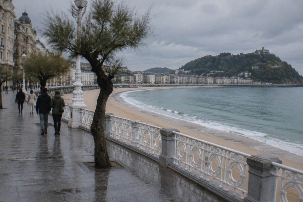 People in casual jackets walking along the La Concha promenade in San Sebastián on an overcast day