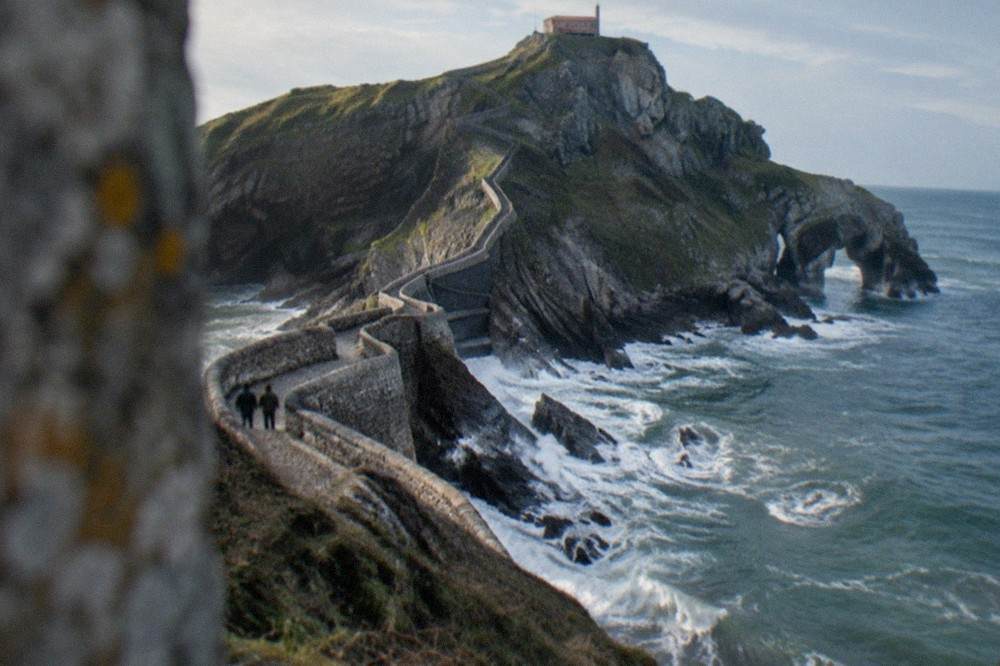 The stone causeway crossing to the rocky islet, with waves breaking against the rocks on either side