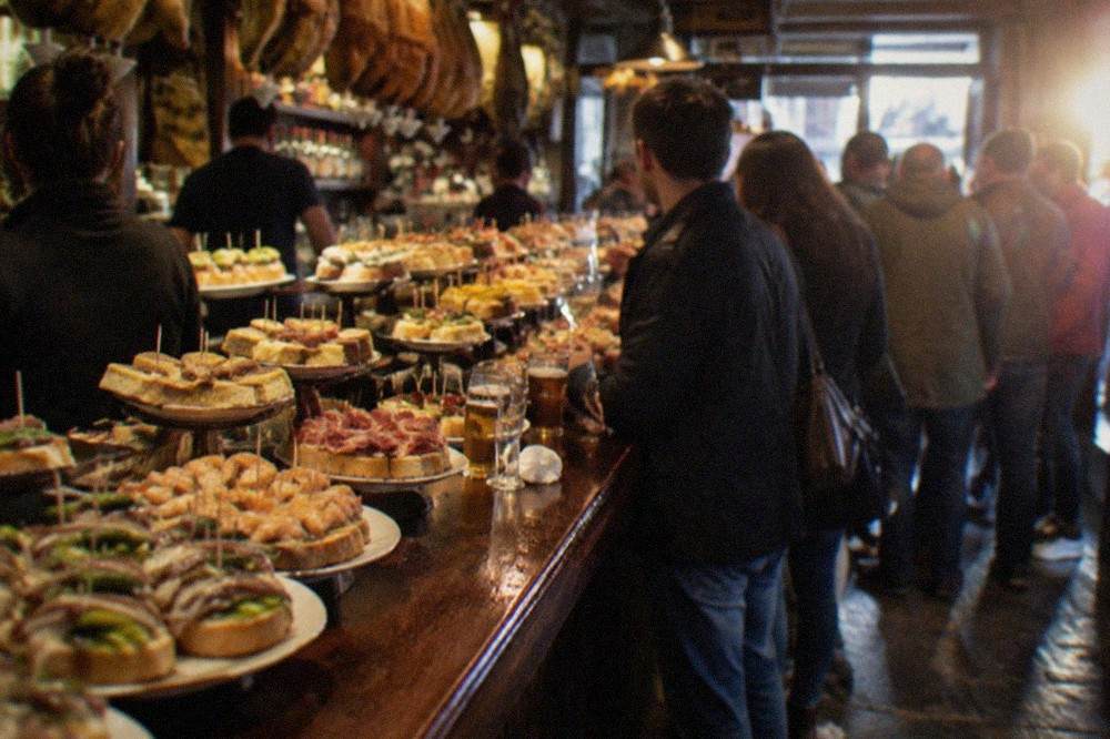 Pintxo bars with crowds standing at the counter in the Old Town of San Sebastián at evening
