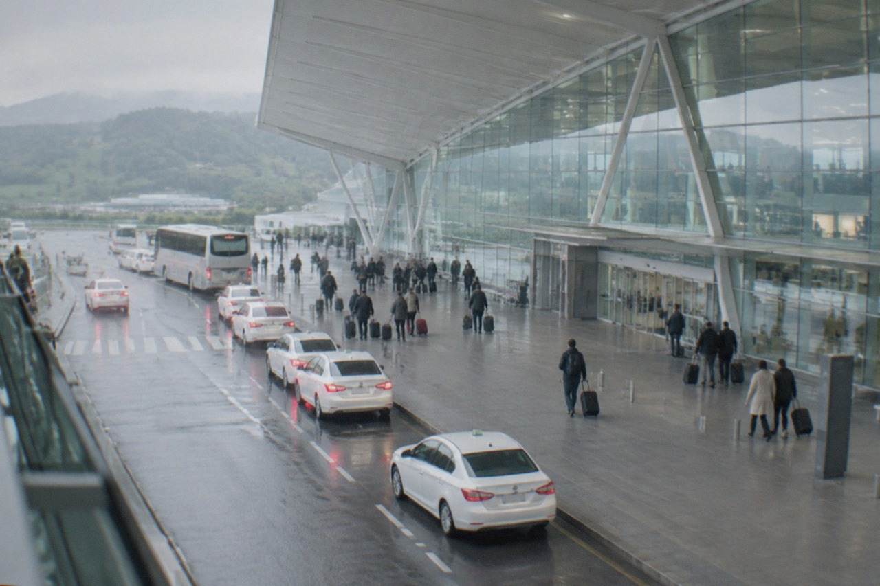 Taxis waiting in a rank outside a modern airport terminal on a grey day