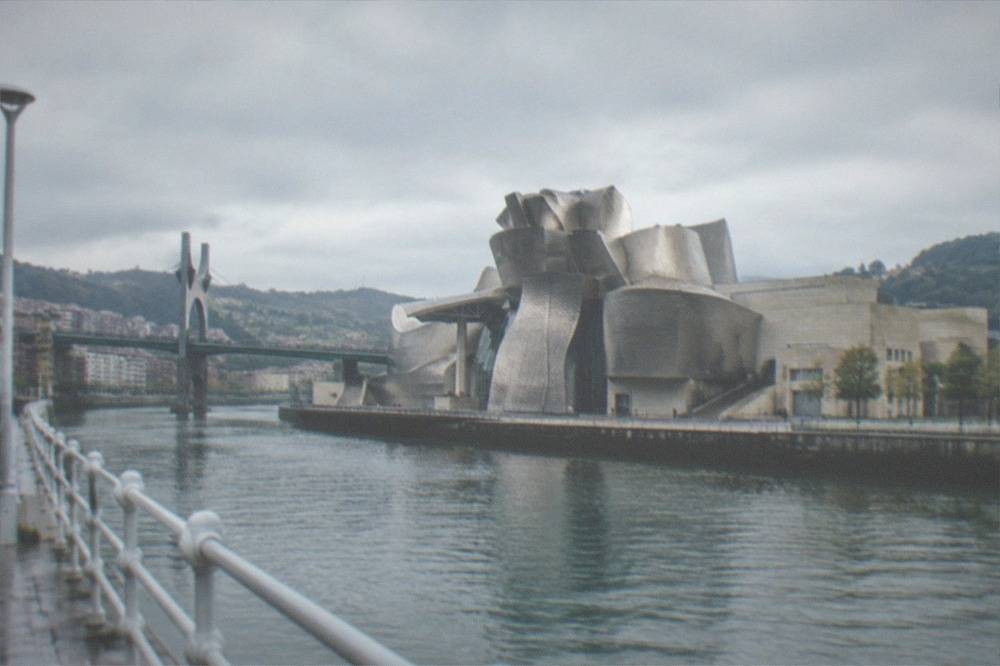 A modern art museum with curved titanium walls beside a river