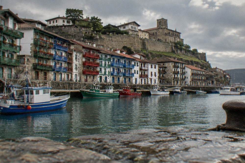 Fishing boats moored in the harbour at Hondarribia with the old town rising behind