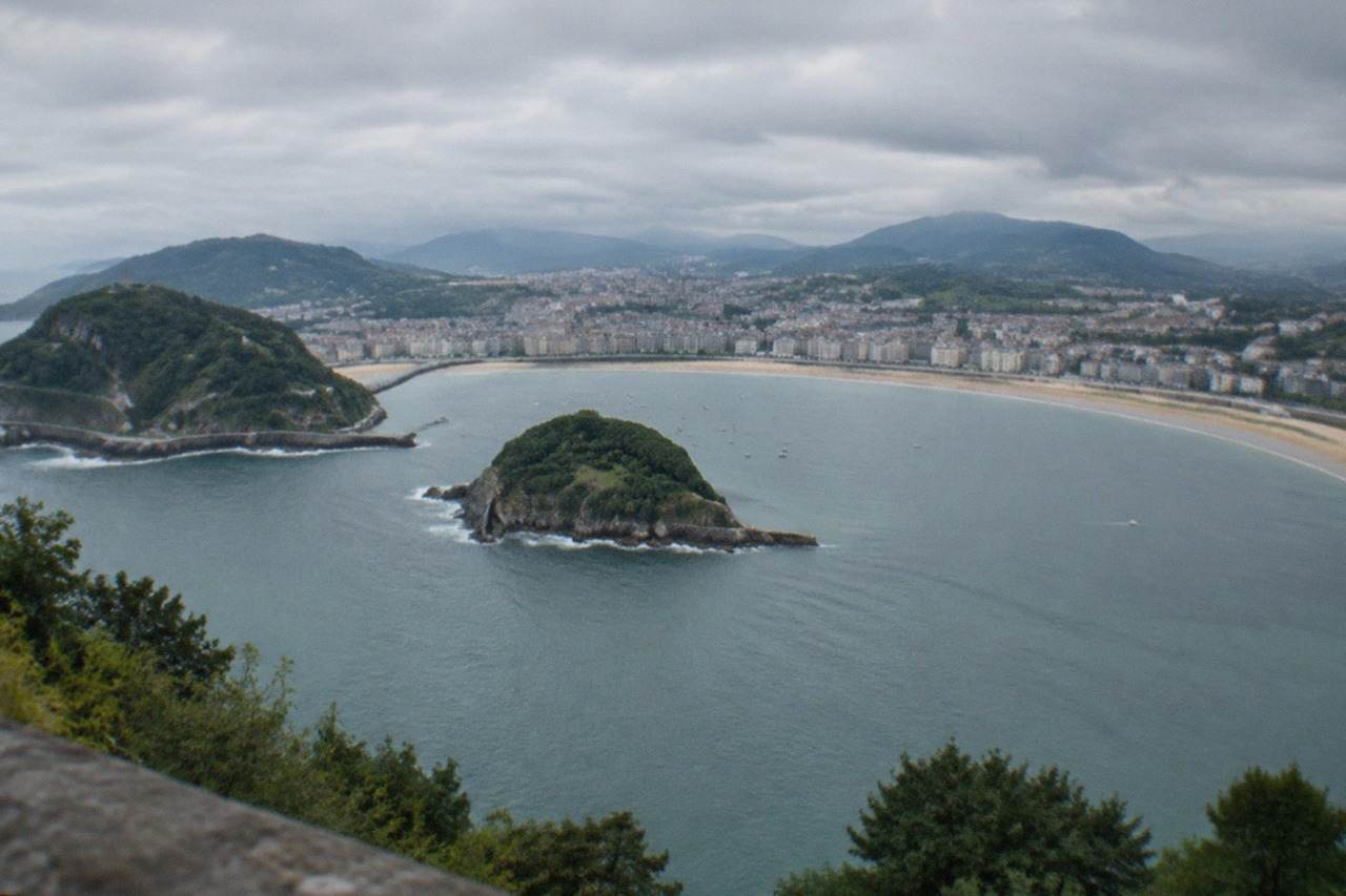 The curved bay of La Concha in San Sebastián seen from above, with the beach, island and green hills