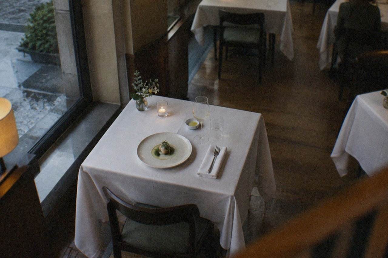 A refined restaurant dining room with set tables and warm evening light