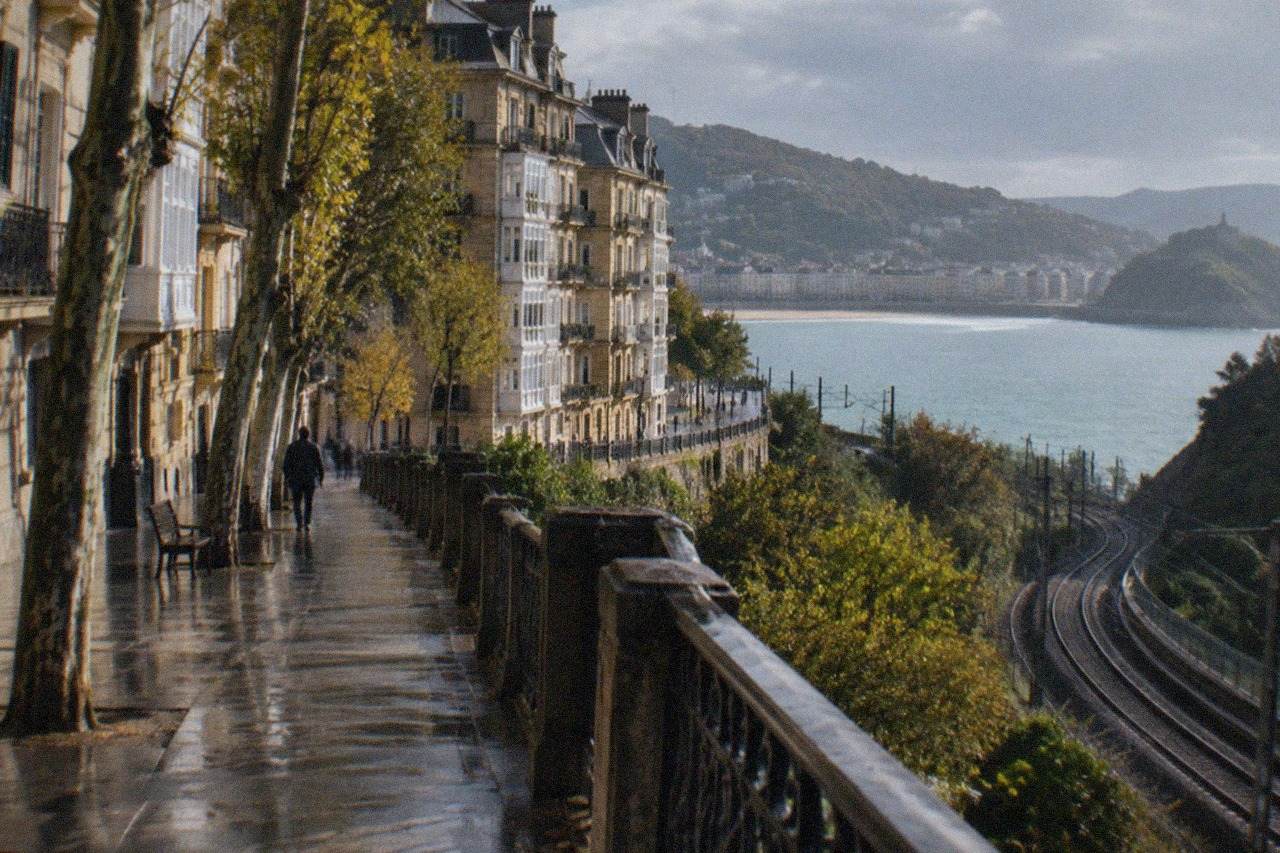 Train tracks curving along green hills toward a city on a bay in northern Spain