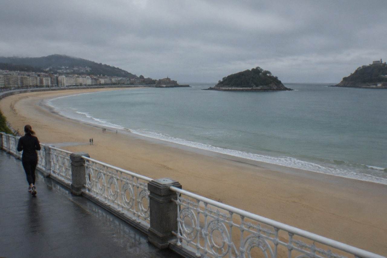 The sandy curve of La Concha beach in San Sebastián seen from above, with the bay and Santa Clara island beyond