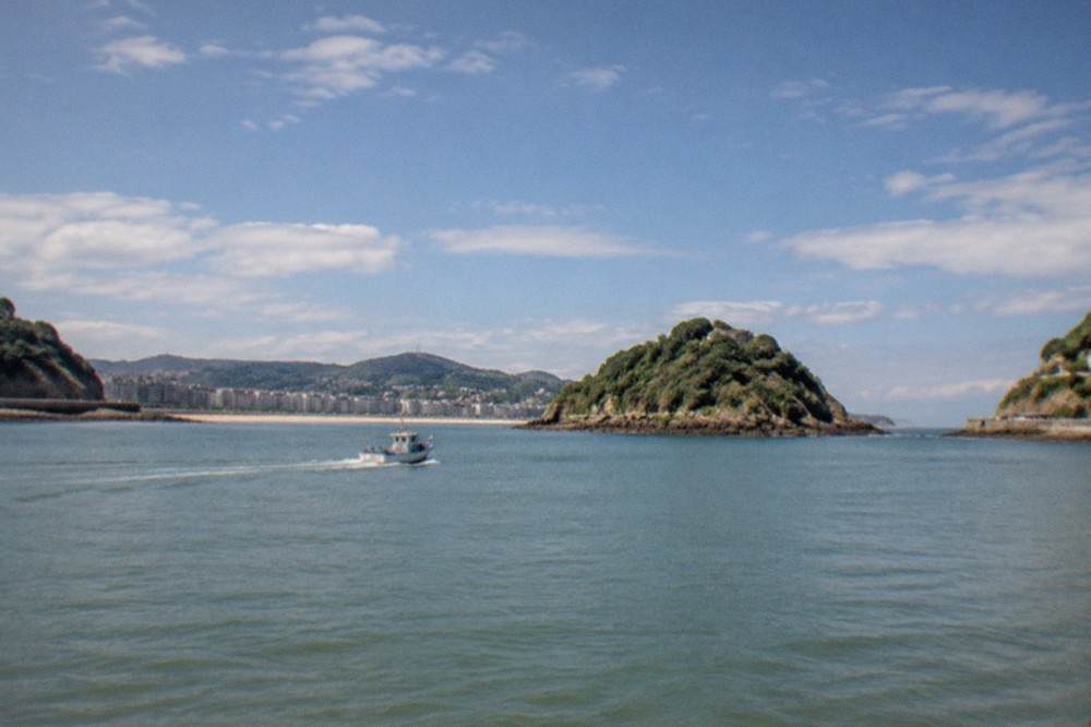 A small boat crossing La Concha bay toward Santa Clara island on a clear afternoon
