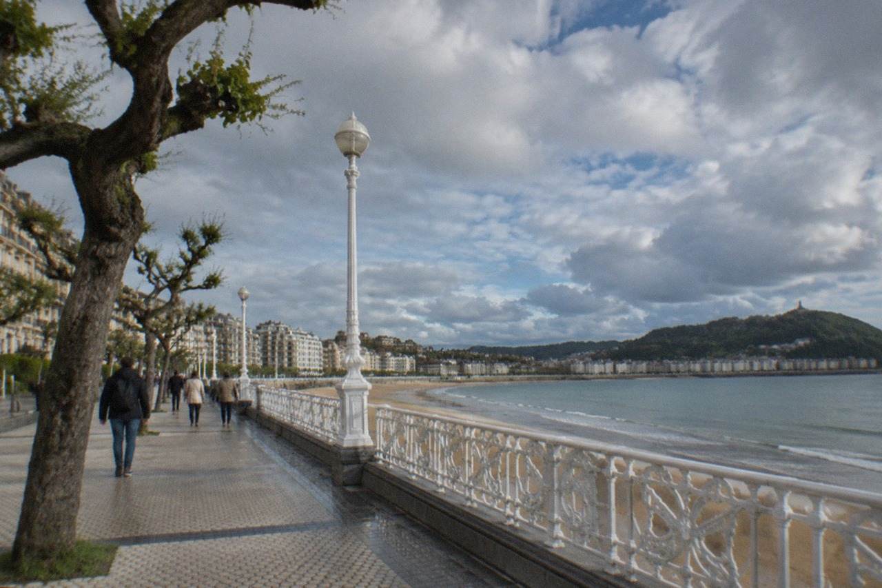 Pedestrians walking along the promenade beside La Concha bay in San Sebastián