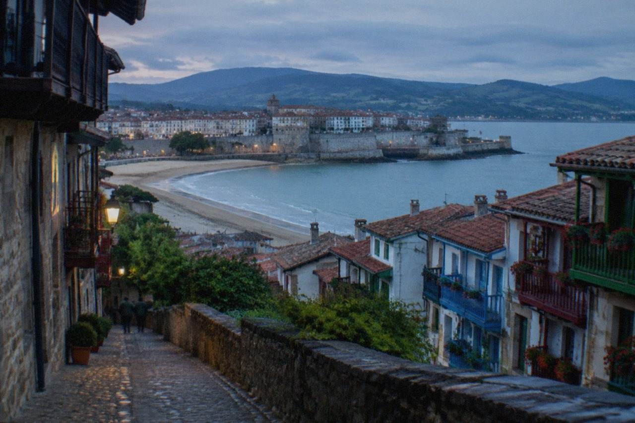 A sandy beach along the Bidasoa estuary with a walled town and hills behind it