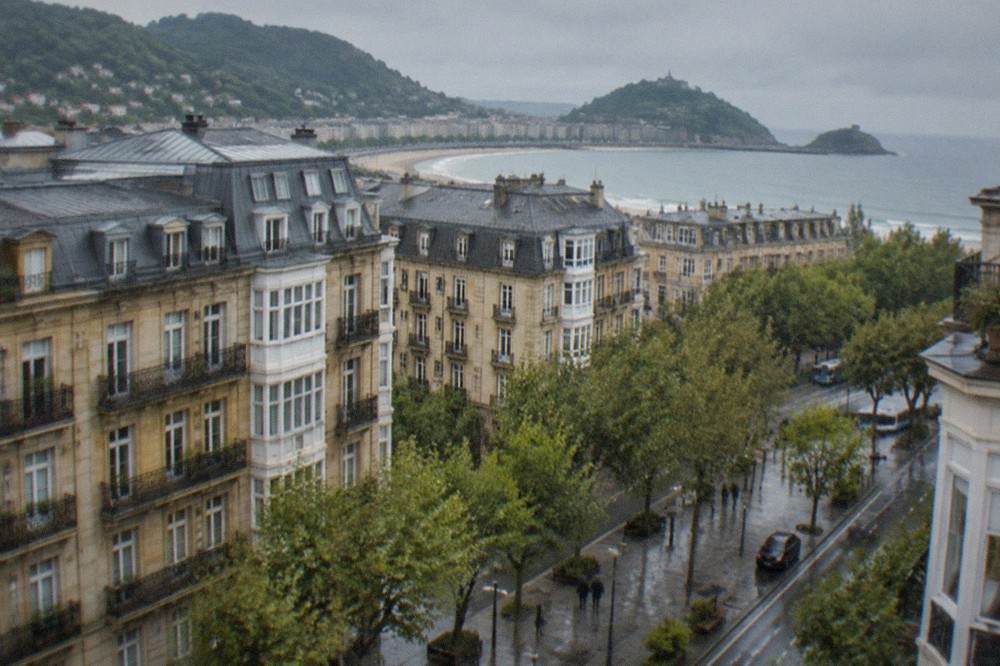 Green hills above the Basque coastline with a small estuary town below and the sea beyond