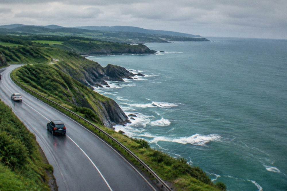 A coastal road winding along green cliffs above the Bay of Biscay in the Basque Country