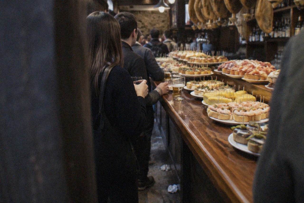 Pintxo bars with hanging hams and crowded counters in the Old Town of San Sebastián at night