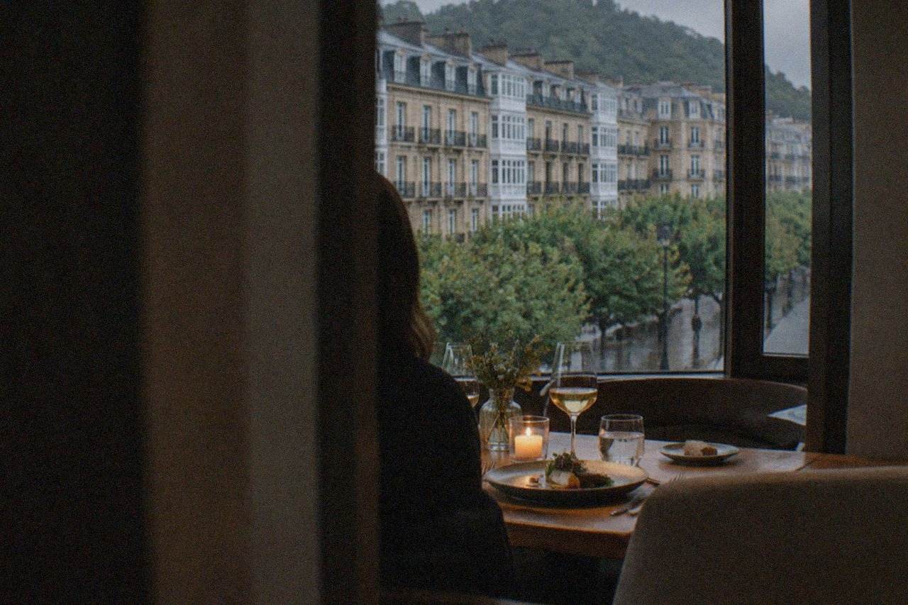 A candlelit dining room with a plated tasting menu dish on a white tablecloth in a restaurant in San Sebastián