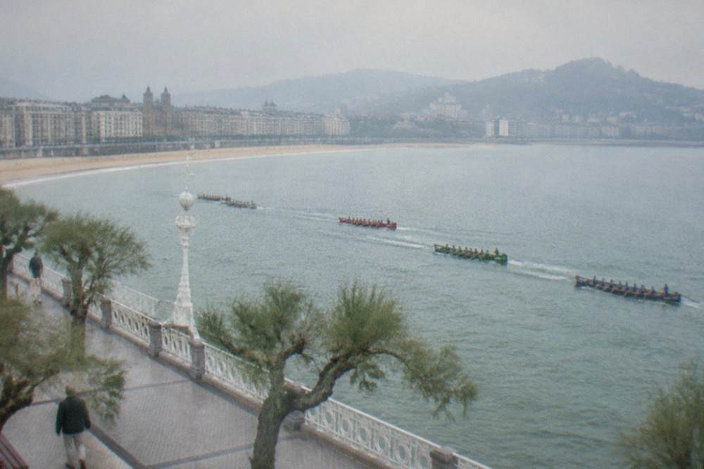 Rowing trainera boats racing across La Concha bay in front of the San Sebastián promenade