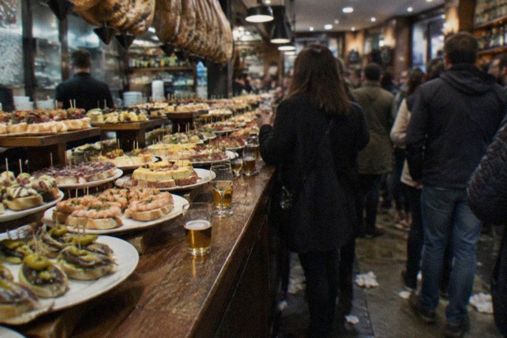 Pintxo bars with crowds standing at the counter in the Old Town of San Sebastián in the evening