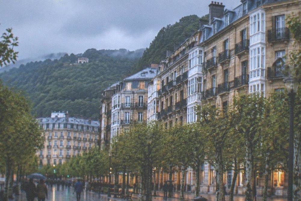Rain clouds over green hills above residential rooftops in San Sebastián
