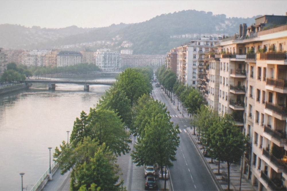 Evening light on apartment balconies and a quiet street in Amara with hills behind