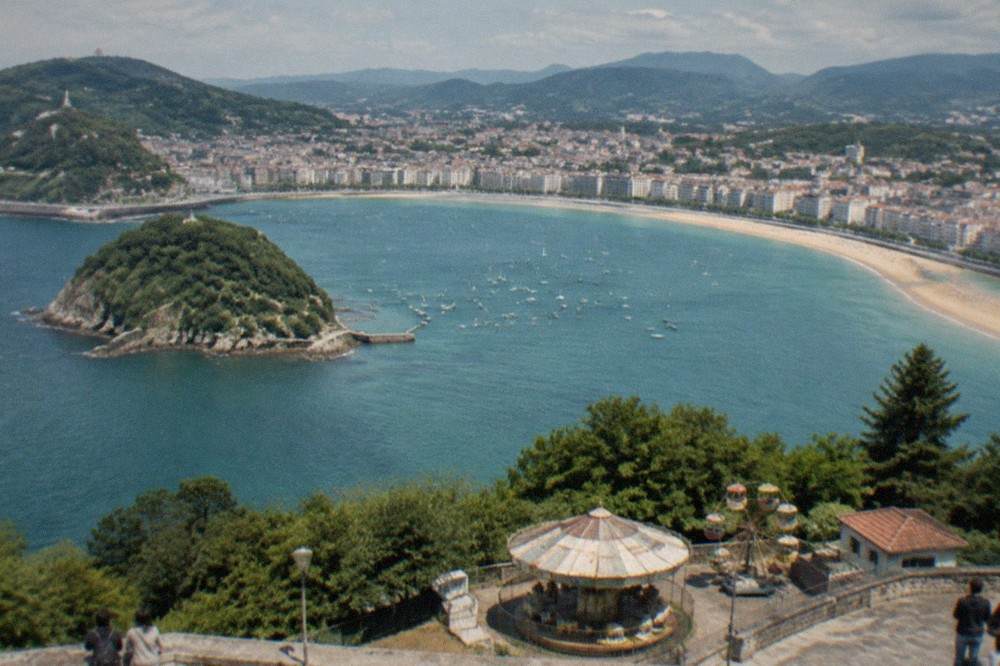Ondarreta beach promenade with parasols and the Monte Igueldo hill behind