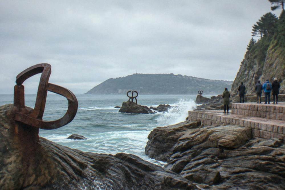 The three steel sculptures of the Peine del Viento on the rocks at the water's edge
