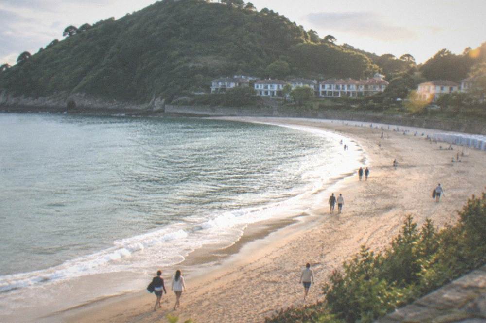 People walking on the sand at Ondarreta beach on a summer afternoon