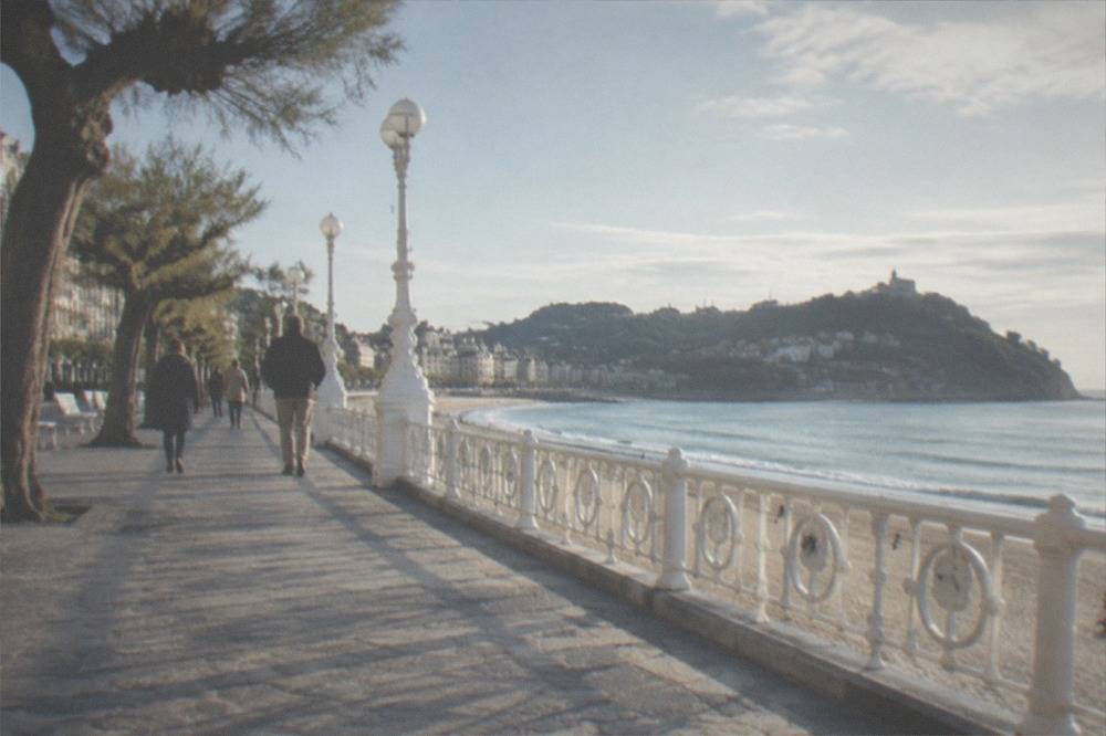 People strolling the La Concha promenade beside the sandy curve of the bay in San Sebastián