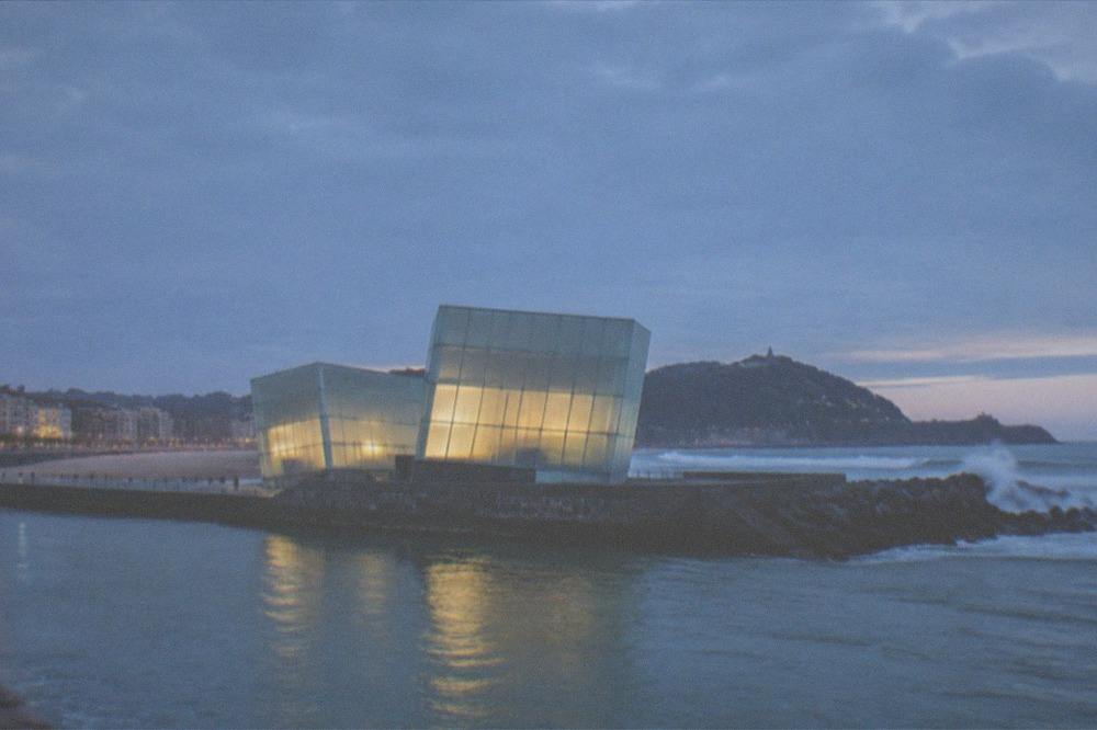 The two glass cubes of the Kursaal building lit at dusk beside the Urumea river mouth in San Sebastián