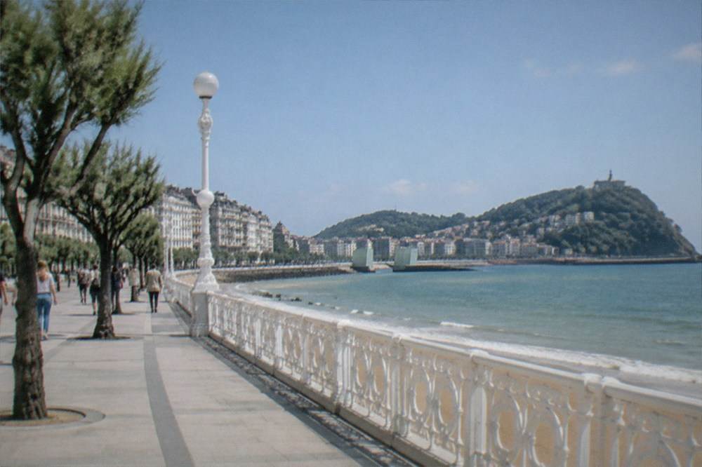 Walkers on the Urumea riverbank promenade with the Kursaal ahead