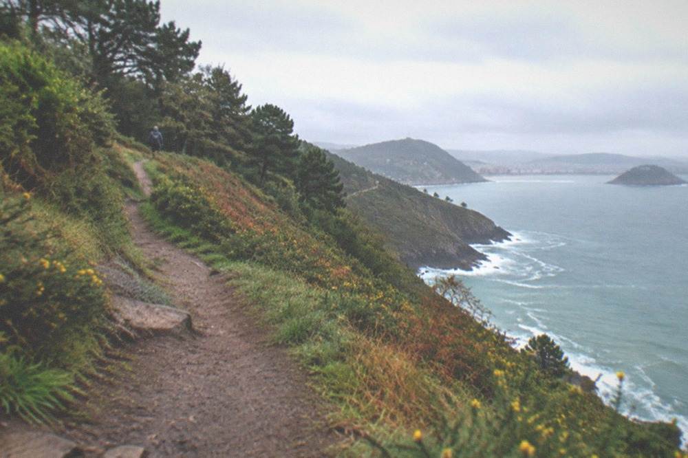 A coastal path on Monte Ulia with the sea below and green hillsides on either side