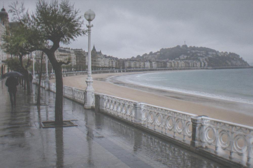 Sandy beach and promenade curving along the bay seen from above the old town