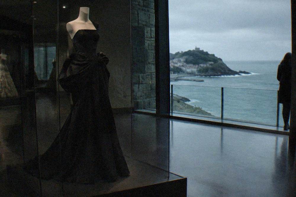 A black Balenciaga evening gown displayed on a mannequin in a dim gallery