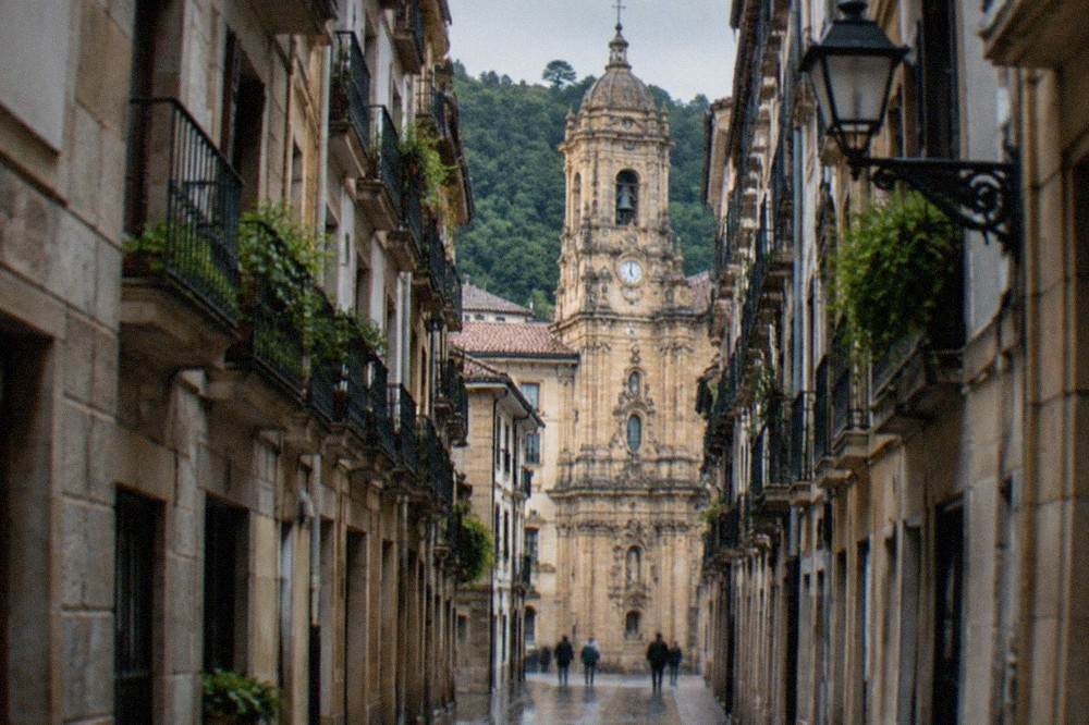 Narrow Old Town street in San Sebastián with the basilica's tower rising above the rooftops
