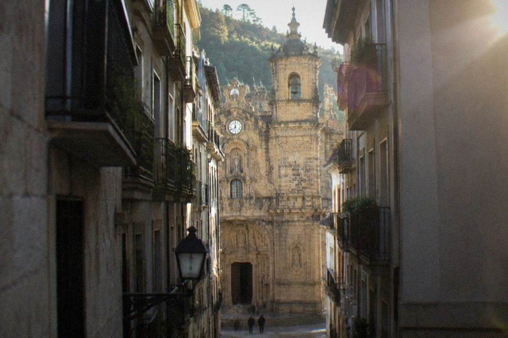 Stone porch and arched doorway of the Basilica of Santa Maria del Coro seen from a narrow Old Town street