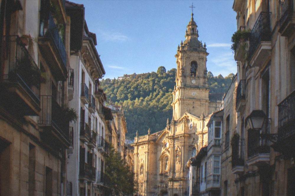 Tall tower of the Basilica of Santa Maria del Coro rising above the rooftops of the Old Town