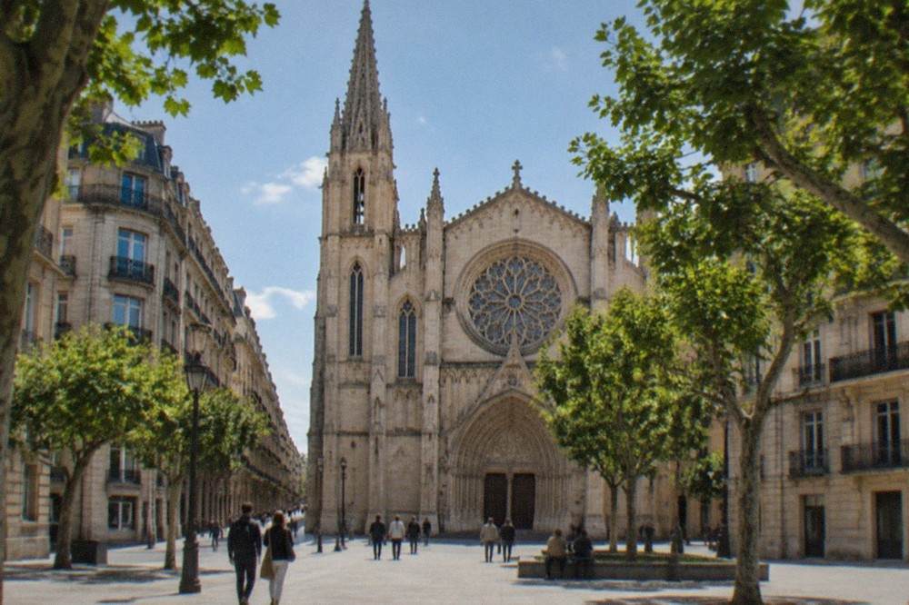 The arched stone entrance and rose window of the cathedral seen from the square.