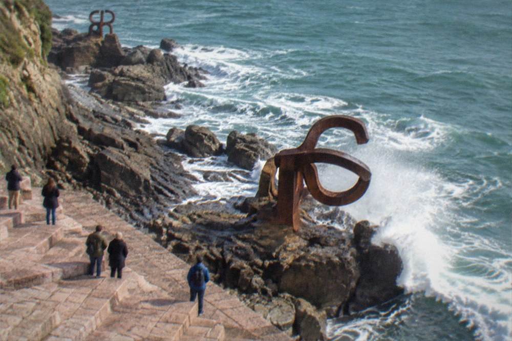 Steel sculptures anchored on wet rocks by the sea at the Peine del Viento in San Sebastián