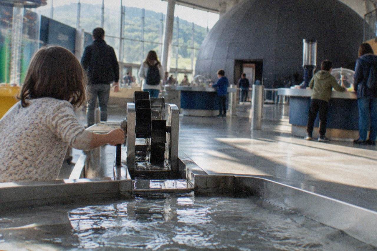 Families exploring interactive science exhibits inside a bright modern museum hall