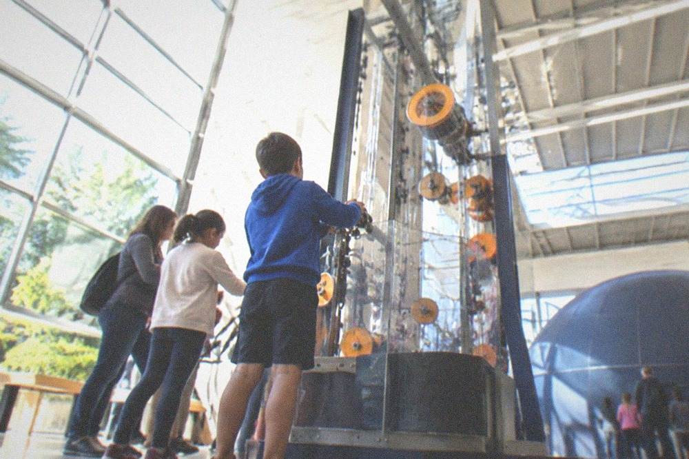 Visitors experimenting with a large hands-on mechanical exhibit in a science hall