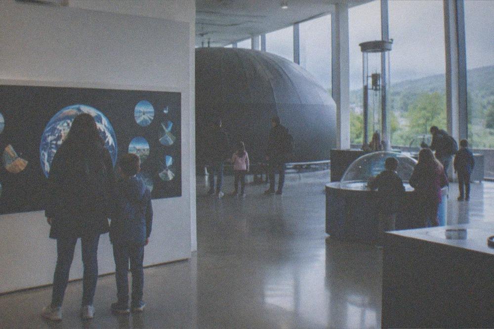 Museum visitors reading a wall display in a bright gallery space