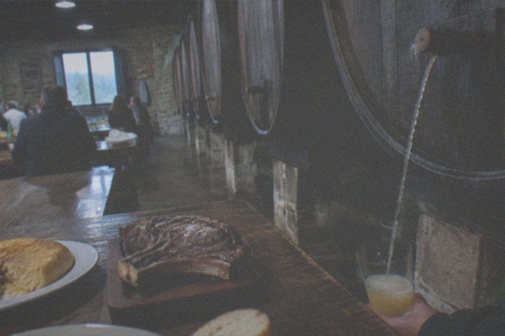A cider barrel with a thin stream of cider being caught in a glass