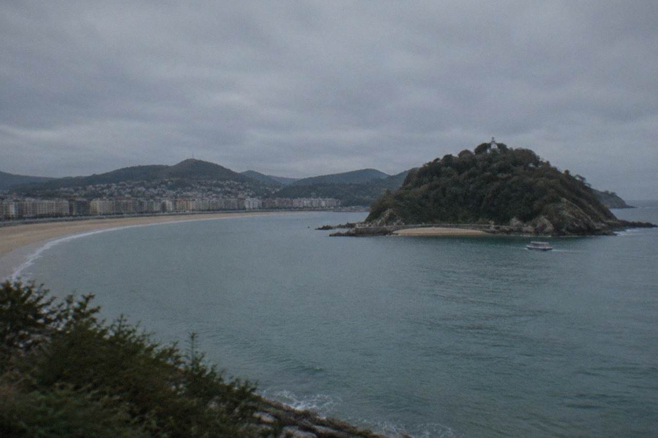 The wide sandy curve of La Concha beach with Santa Clara island in the bay and hills behind