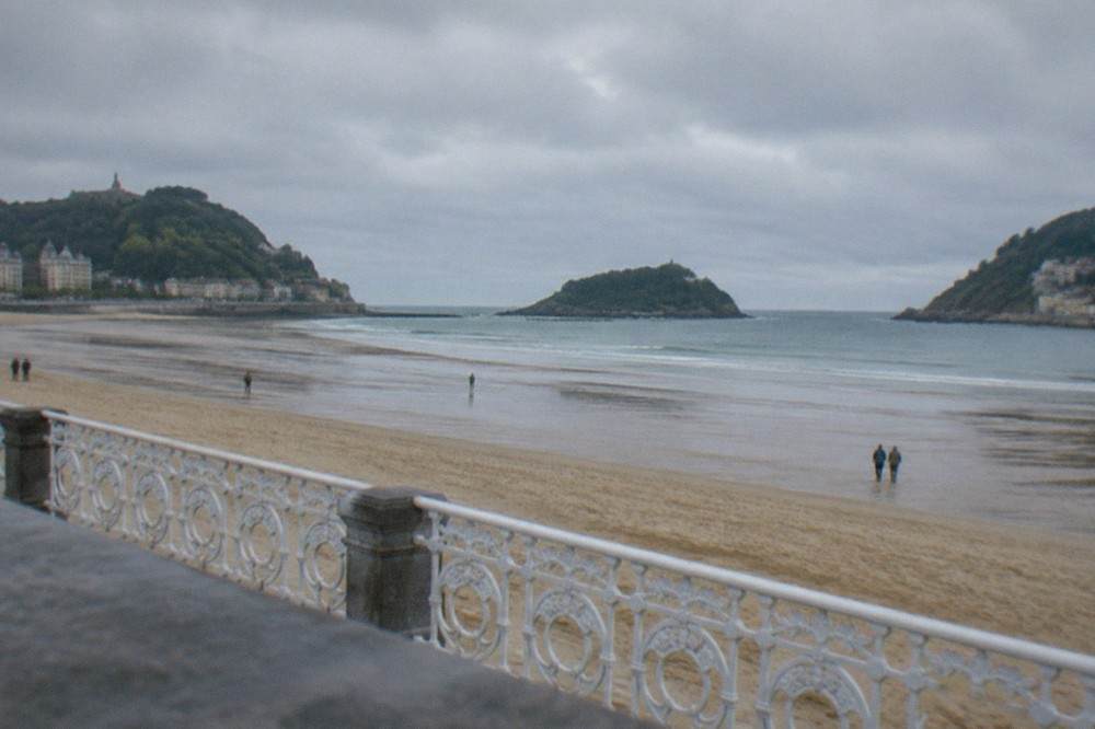 La Concha beach at low tide with wide wet sand and the island in the distance