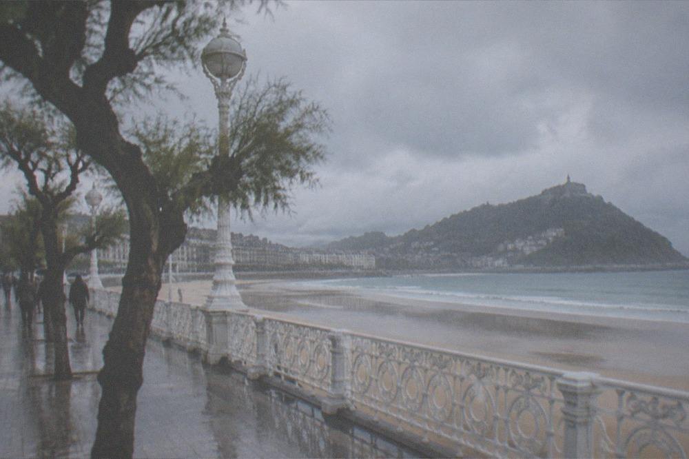 Clouds over La Concha bay with the promenade and wet sand after rain
