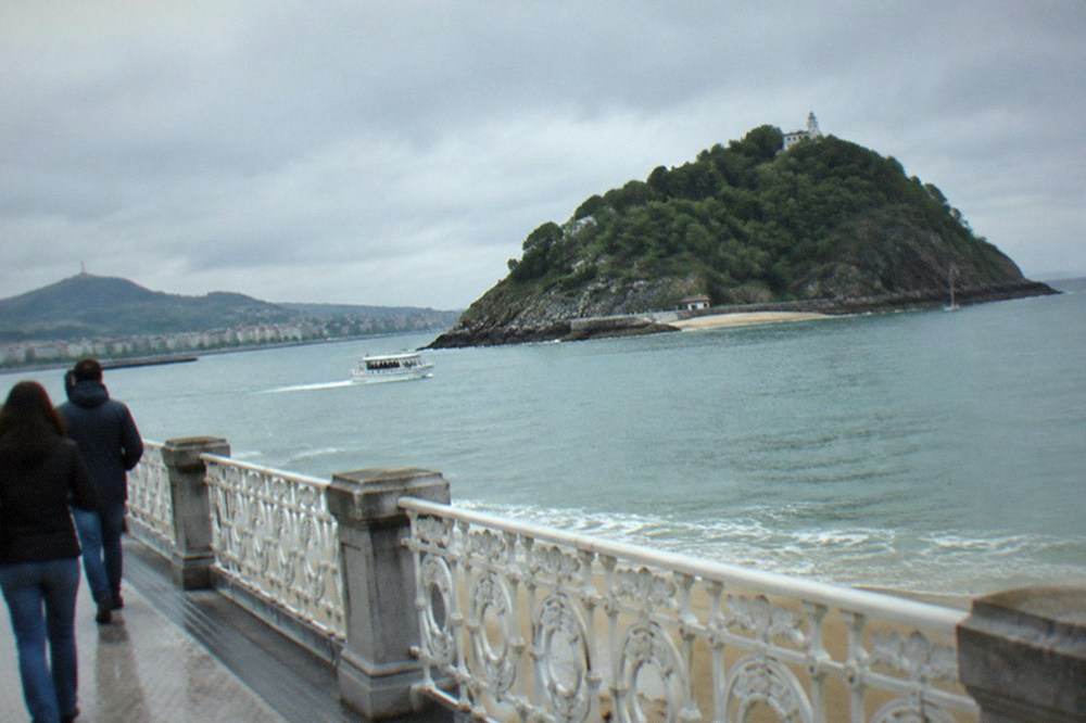 Walkers on the La Concha promenade with the bay and Santa Clara island beyond