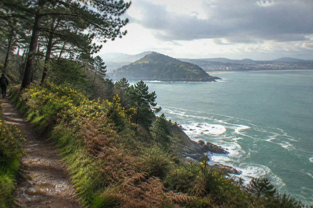 Clifftop path through low woodland on Monte Ulia with the sea below