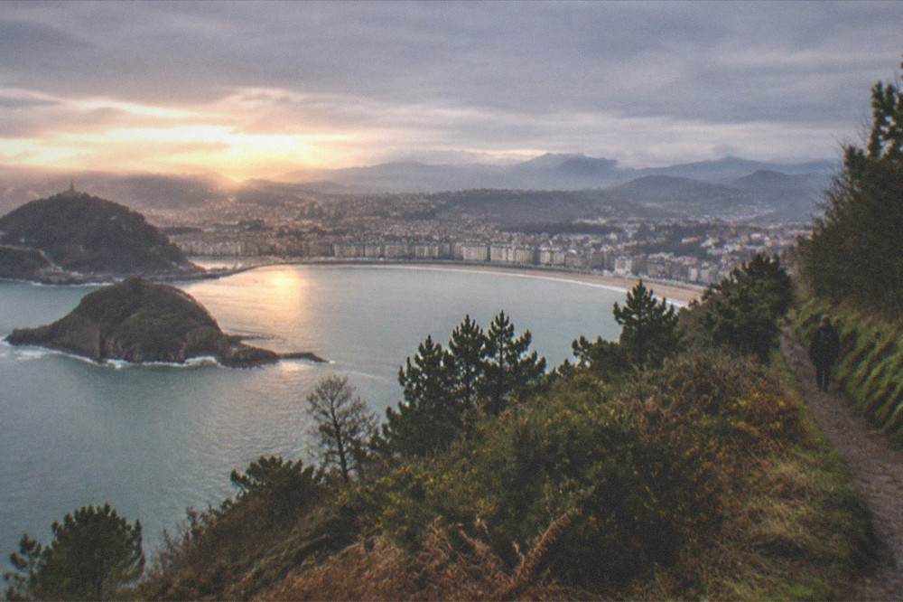 Evening view across the city from elevated ground with warm light on the bay