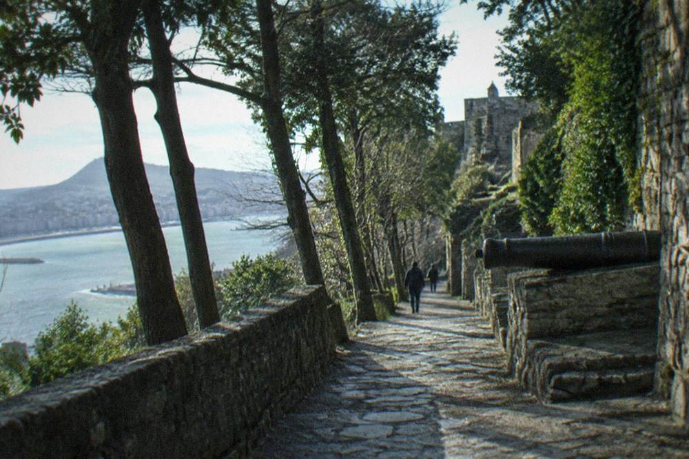 Path climbing through trees on Monte Urgull toward the summit fortress