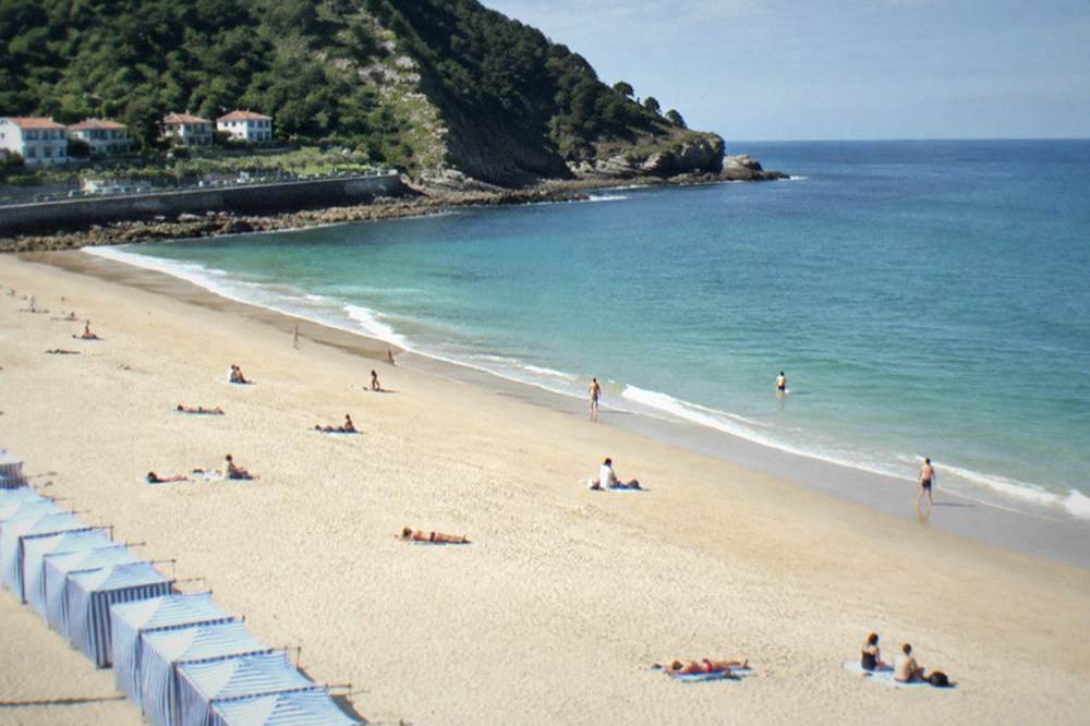 People relaxing on towels on the wide sand of Ondarreta Beach
