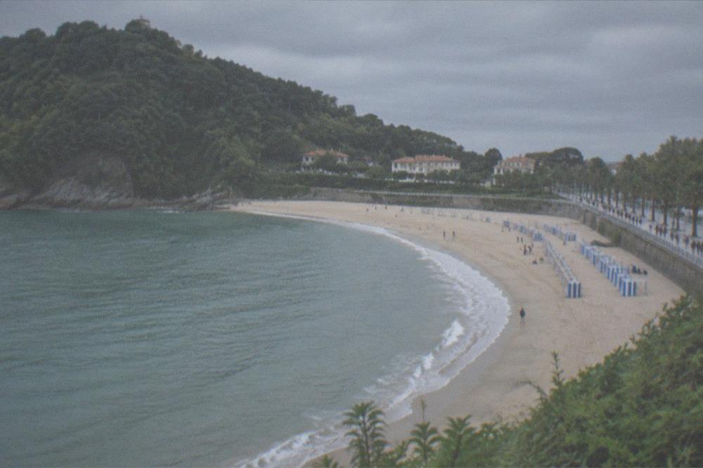 The seafront promenade behind Ondarreta Beach with walkers and palm trees